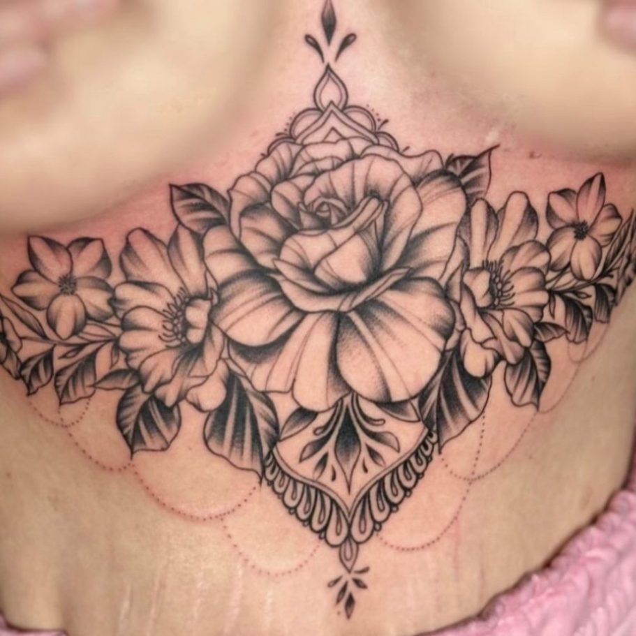 Schwarze Blumen-Tätowierung mit einer großen Rose und kleinen Blumen im Hintergrund.