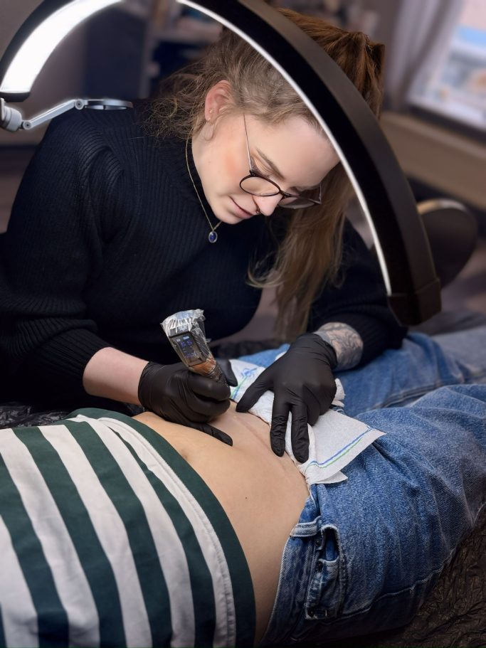 Alicia Funck beim Tätowieren an einer Narbe
