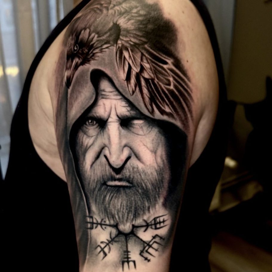 Detailreiche Tätowierung eines älteren Mannes mit Kapuze und einem Adler auf der Schulter.