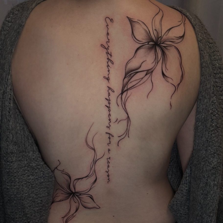 Tattoo auf dem Rücken mit Blumenmotiven und dem Schriftzug "Everything happens for a reason".