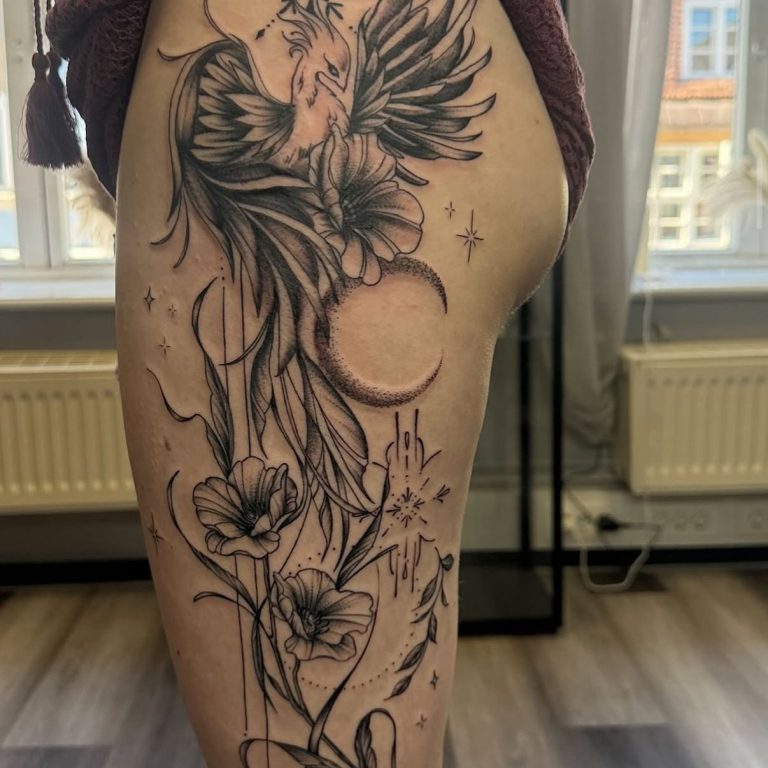 Tattoo auf dem Oberschenkel mit einem Vogel, Blumen und Mondmotiven.
