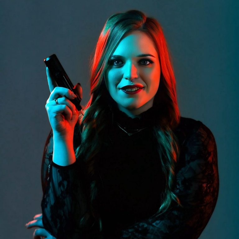 Alicia Funck umgeben von blauen und roten Lichtern mit Tattoomaschine in der Hand.