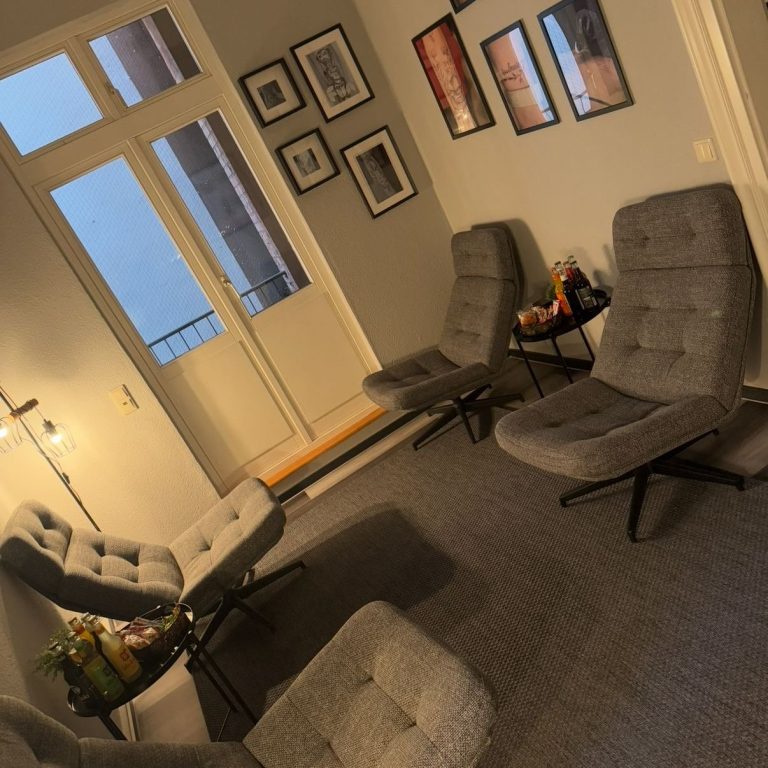 Gemütlicher Raum mit grauen Sesseln und Kunst an den Wänden, Fenster mit Aussicht.